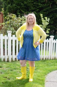A fun outfit featuring yellow Hunter Rain Boots, a blue lace dress, and yellow cardigan