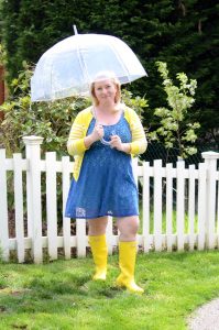 A fun outfit featuring yellow Hunter Rain Boots, a blue lace dress, and yellow cardigan