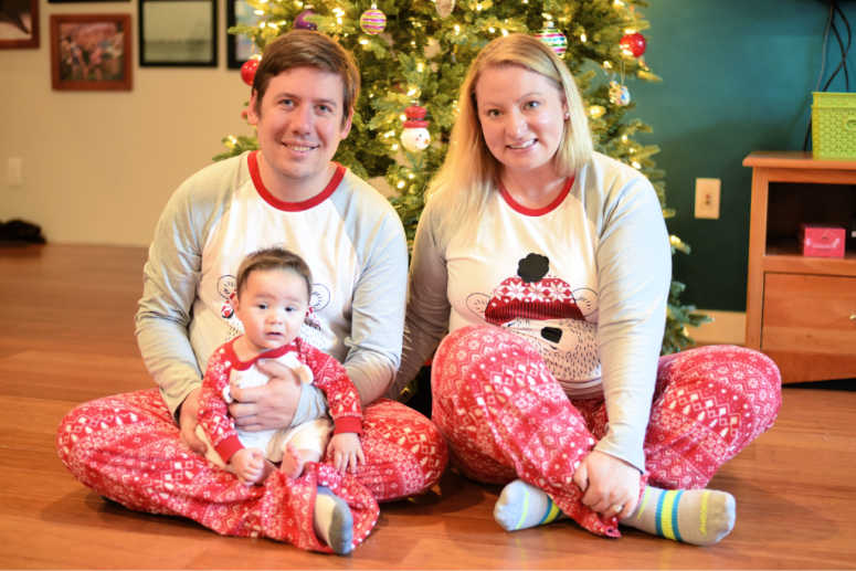 family in pajamas sitting in front of a Christmas tree