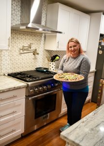 Woman holding pizza in kitchen