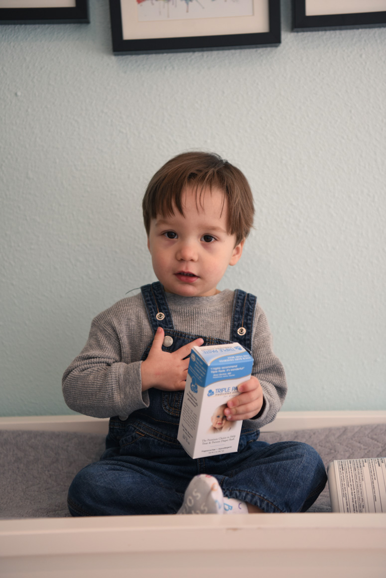 Toddler holding a box of triple paste diaper cream.