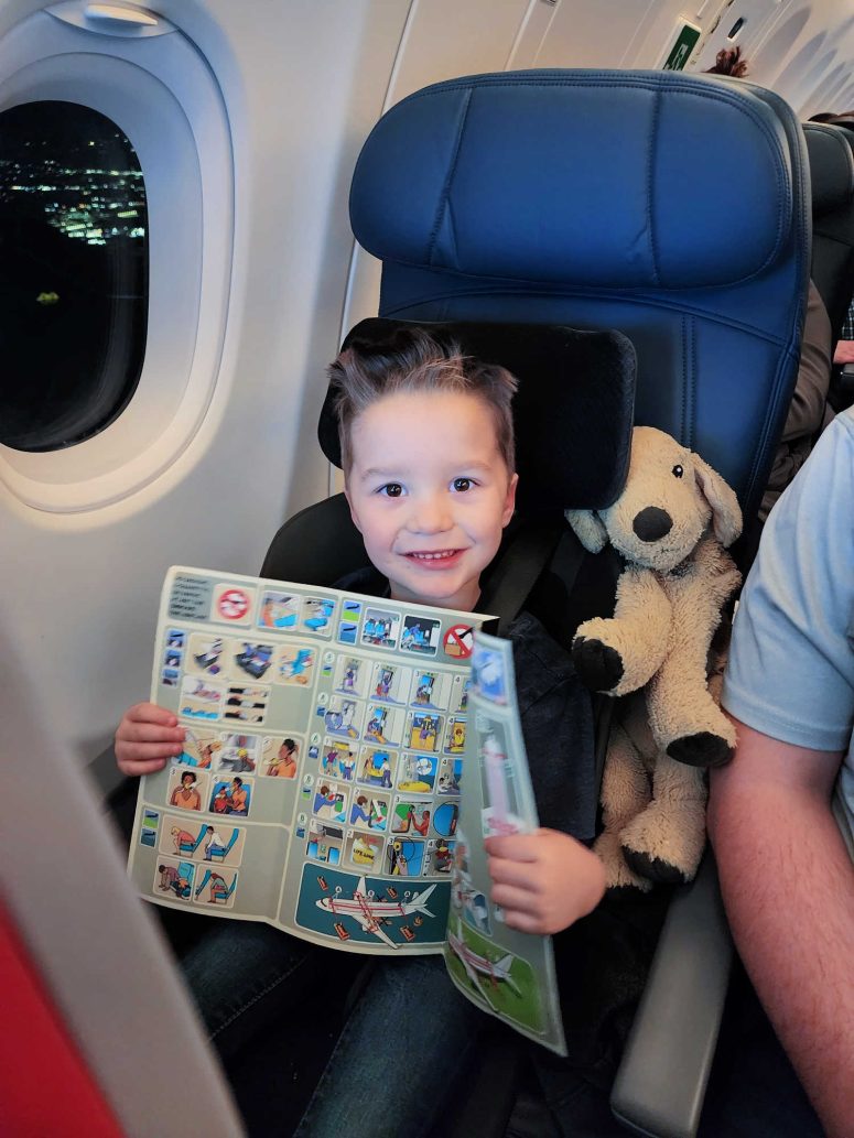 A toddler boy smiling while holding the Delta safety card